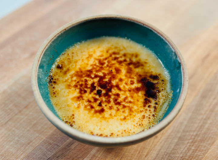 Vegan Maja Blanca with caramelized top in teal bowl on wooden board.